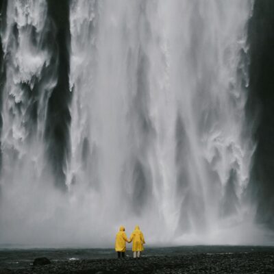 Anonymous travelers holding hands against spectacular waterfall