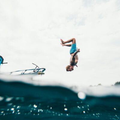 Man Wearing Blue Shorts About to Dive on Body of Water