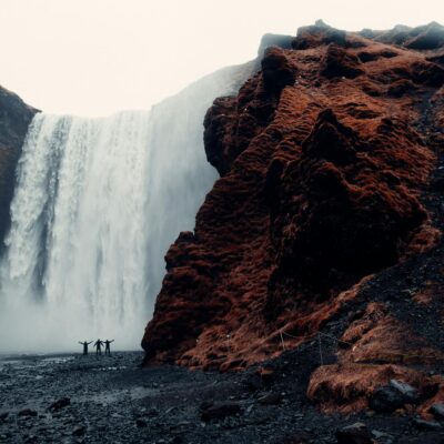 Three Men Standing Near Waterfalls